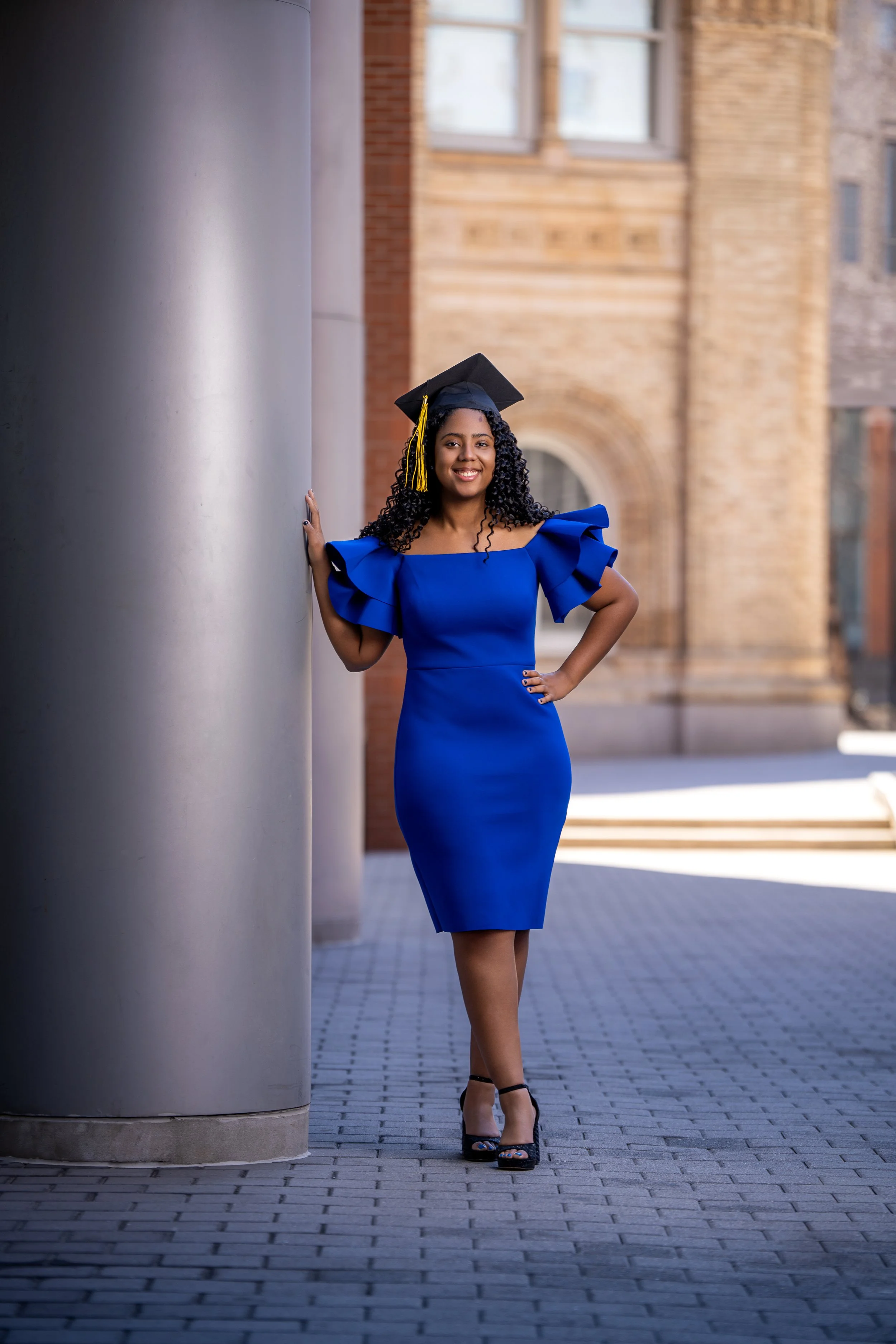 Philadelphia graduation photographer capturing full body portrait of female graduate in blue dress and cap outdoors