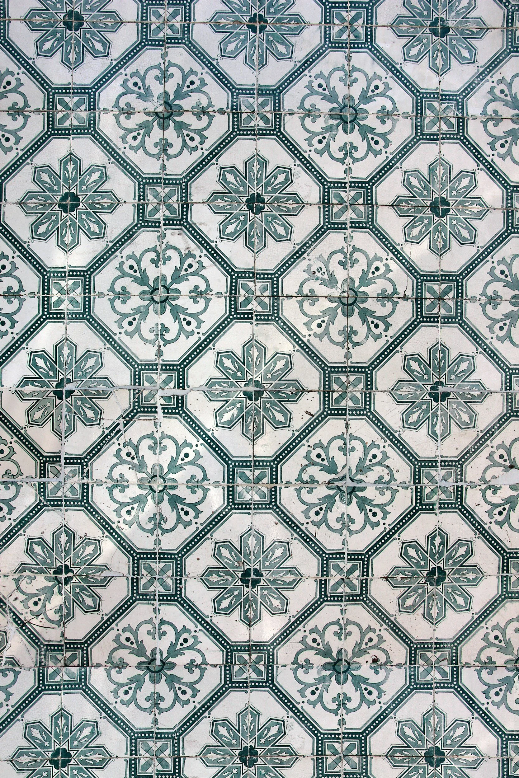 Pattern of decorative ceramic tiles with teal, white, and gray geometric and floral designs.
