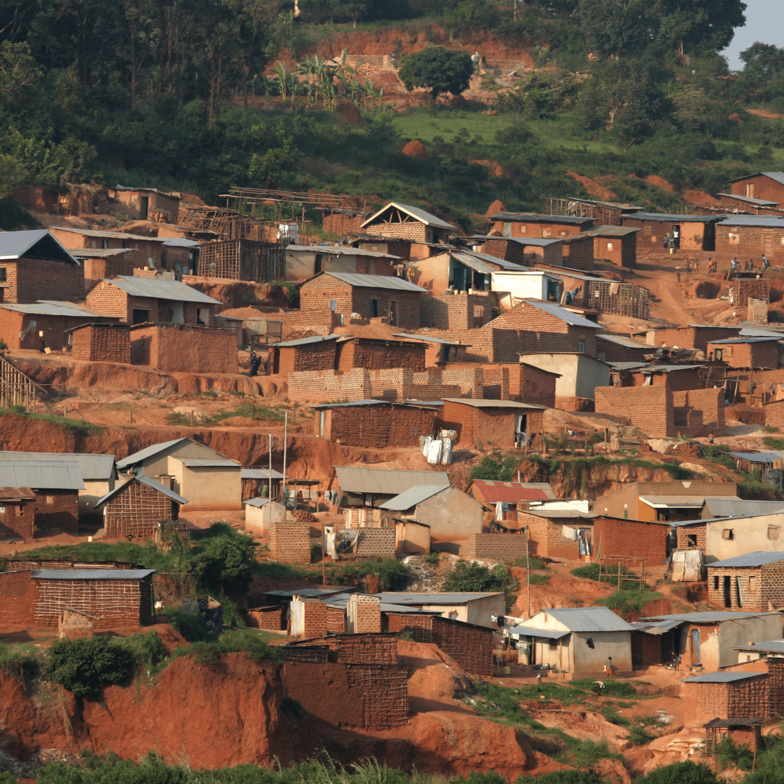 Hilly landscape with small brick houses and sparse vegetation.