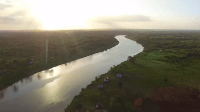 Aerial view of a winding river flowing through lush green fields during sunset.
