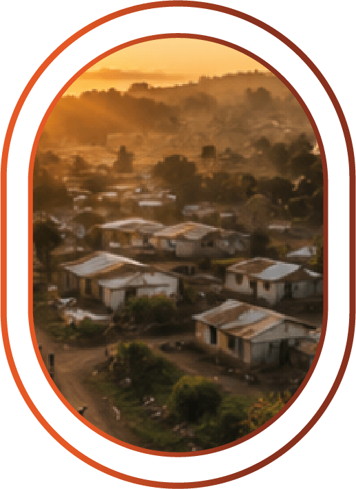 Aerial view of a small village with simple houses at sunset, surrounded by trees and hills.