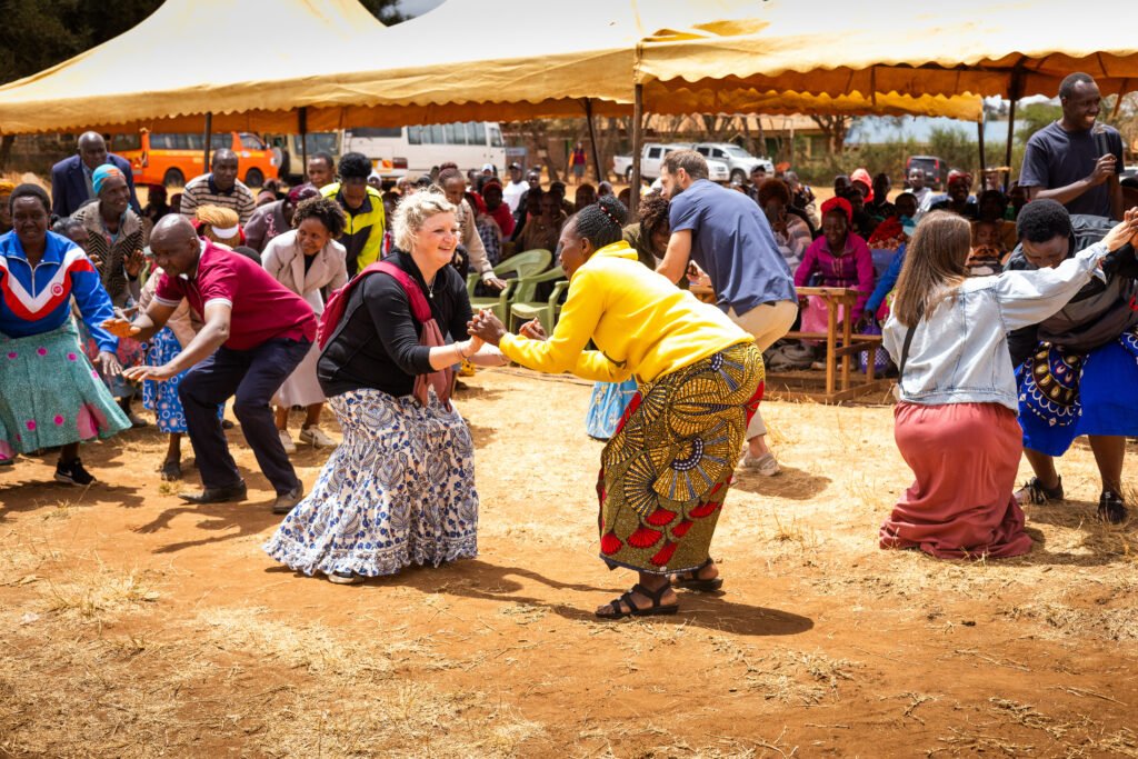 People dancing and celebrating under a yellow tent at an outdoor event.