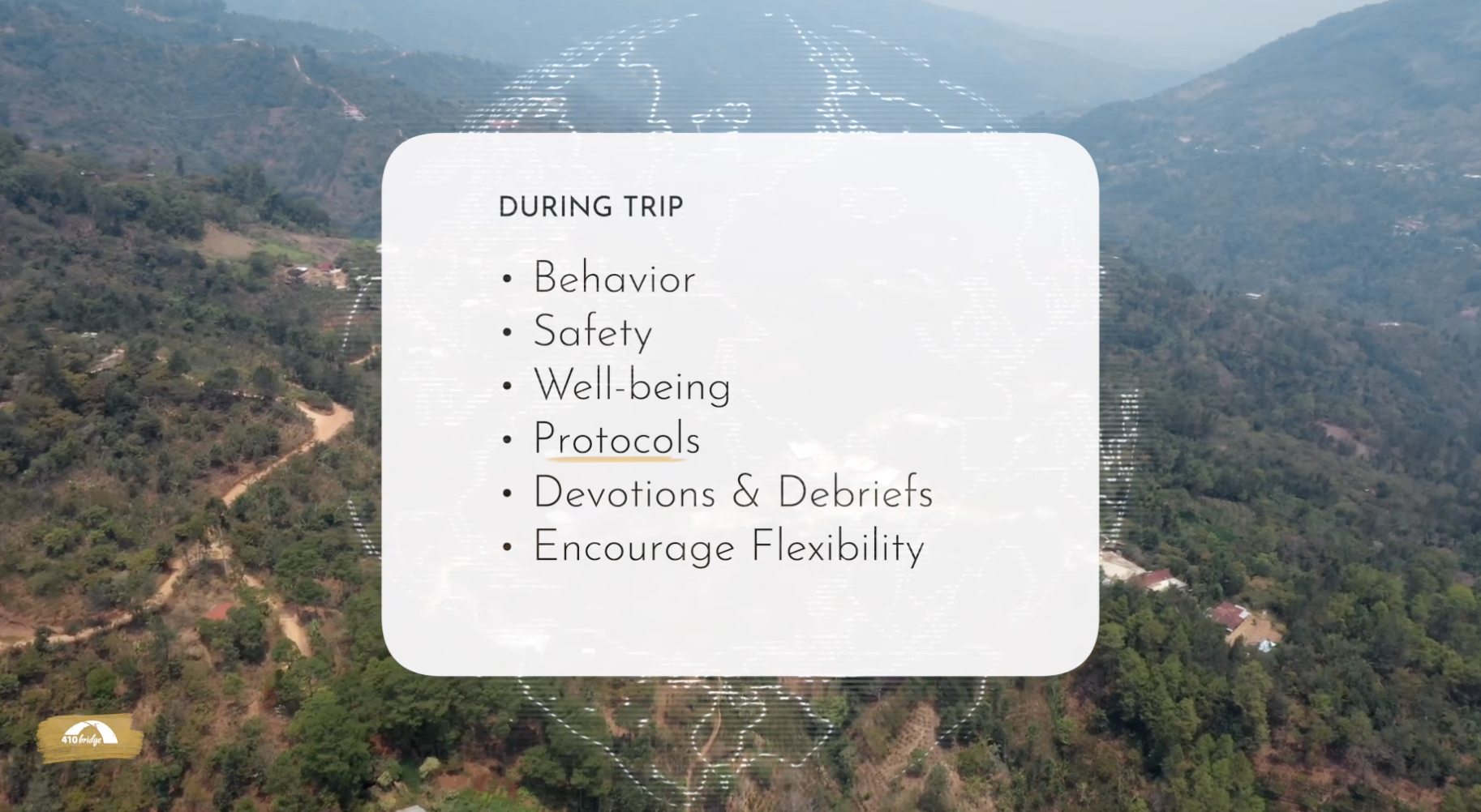 Aerial view of a mountainous landscape with dirt roads and scattered houses. Overlaid in the center is a semi-transparent white rectangle containing a list titled 'DURING TRIP' with bullet points: Behavior, Safety, Well-being, Protocols, Devotions & Debriefs, Encourage Flexibility.