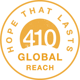 Circular logo with a black background and orange border, containing the text 'Hope That Lasts,' '410,' and 'Global Reach' in orange.