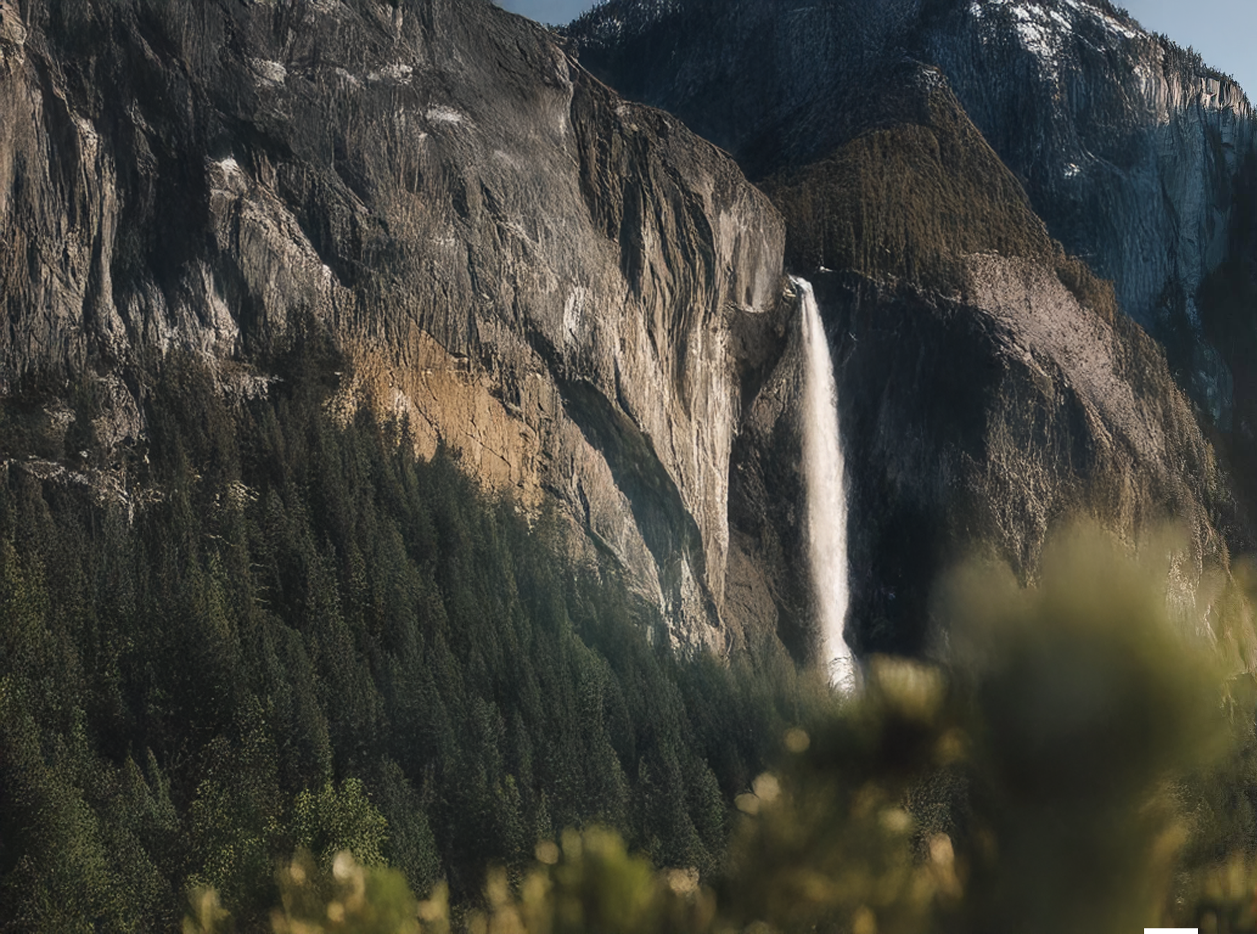 A tall mountain with a cascading waterfall in its center, surrounded by lush green trees.