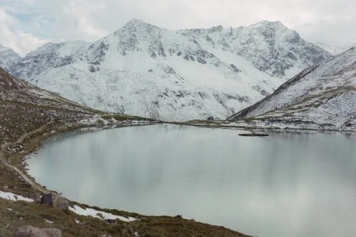 Snow-covered mountains surrounding a calm lake in a mountainous landscape.