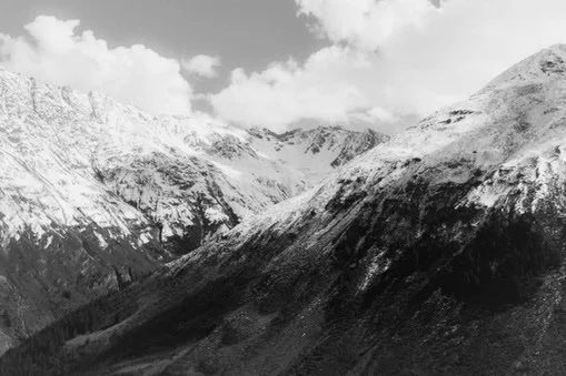 Snow-covered mountain range with cloudy sky in the background.
