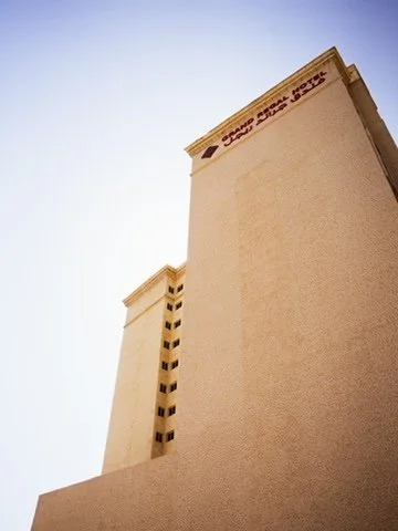 Two tall beige buildings with a clear blue sky in the background.