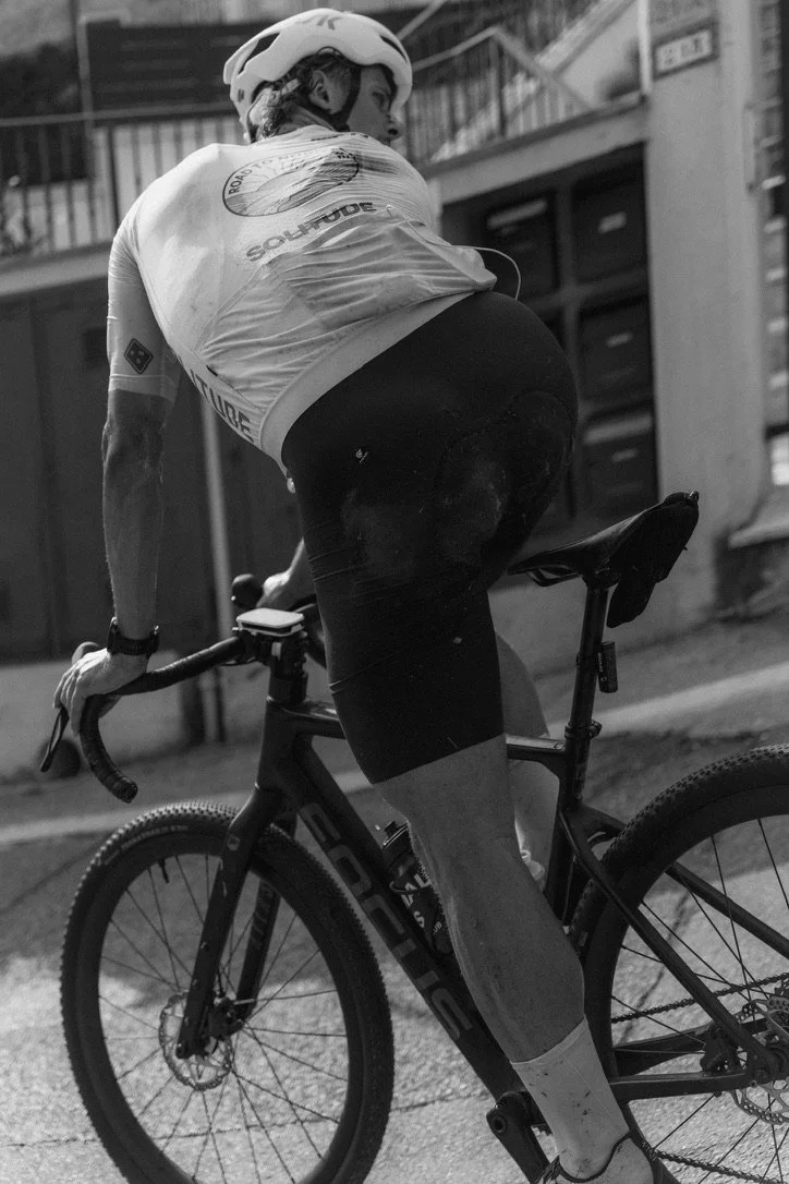 A cyclist wearing a helmet and athletic gear, riding a mountain bike on a street at night.