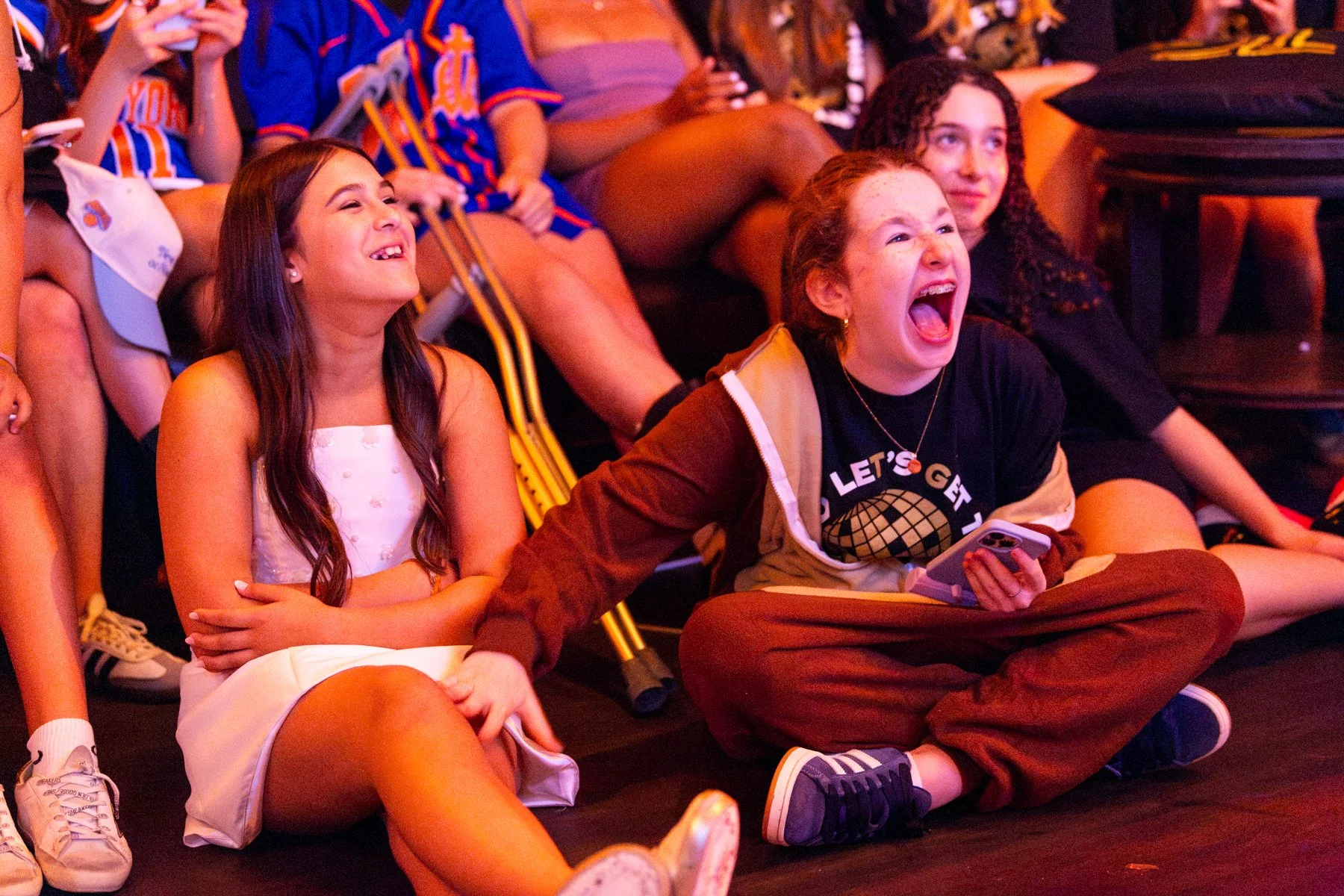 Group of children sitting on the floor, laughing and having fun at an indoor event.