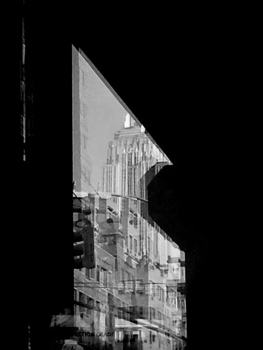 Vista de edificios urbanos a través de un muro con forma de triángulo y línea de cables aéreos en una ciudad