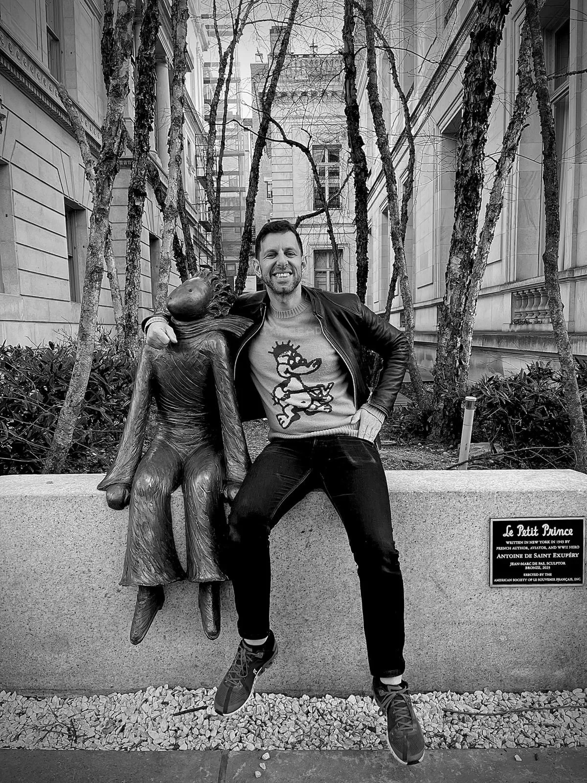 Hombre sonriendo junto a la escultura de "El Principito" en una plaza urbana