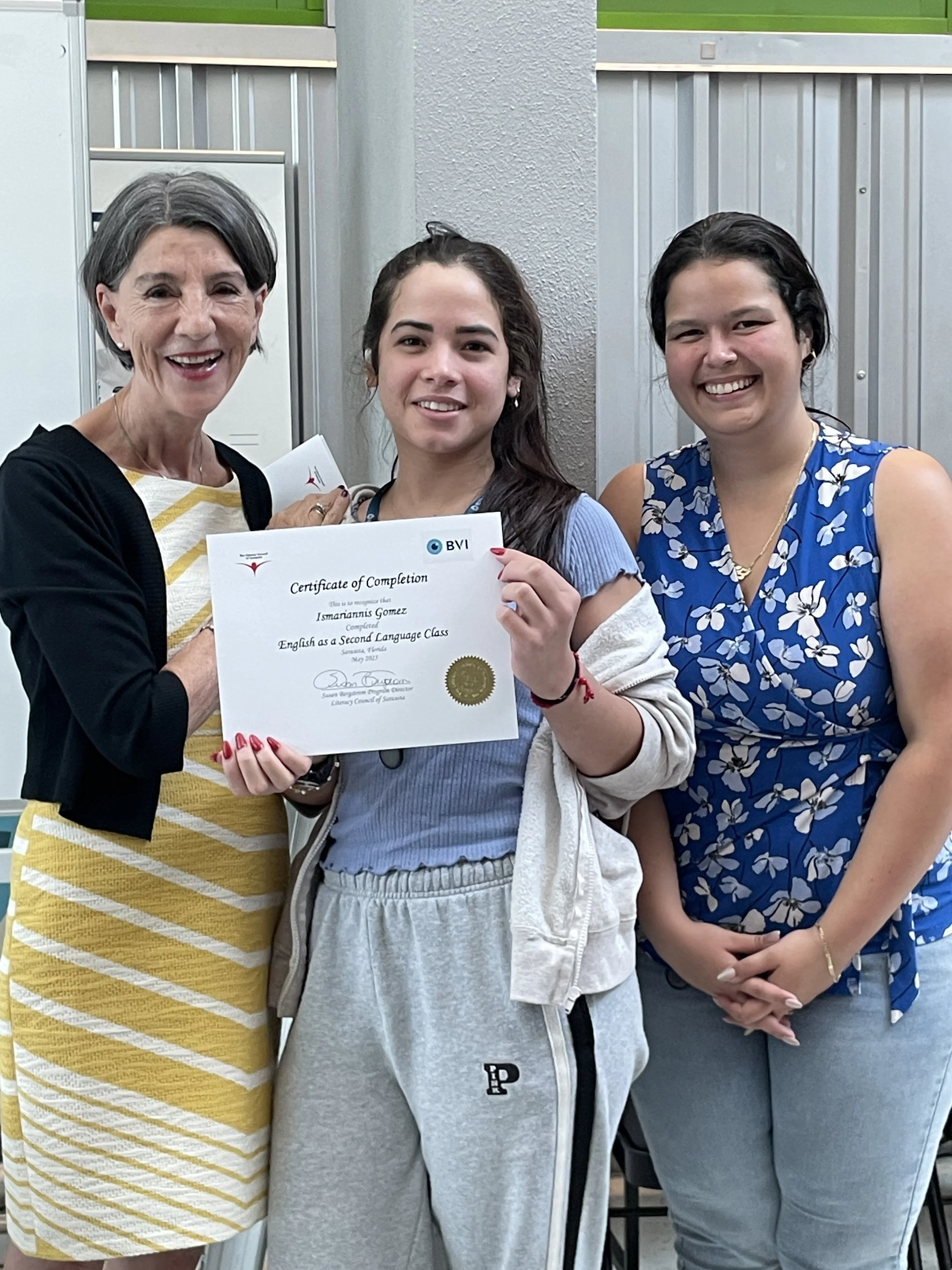 Three women and a girl standing together, with one holding a certificate, smiling.