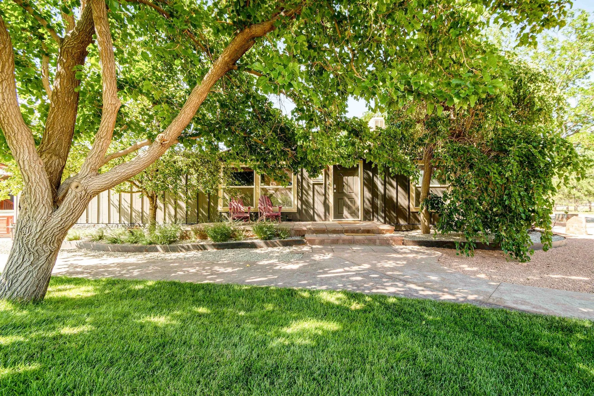 A house with a porch surrounded by trees and a well-maintained lawn.