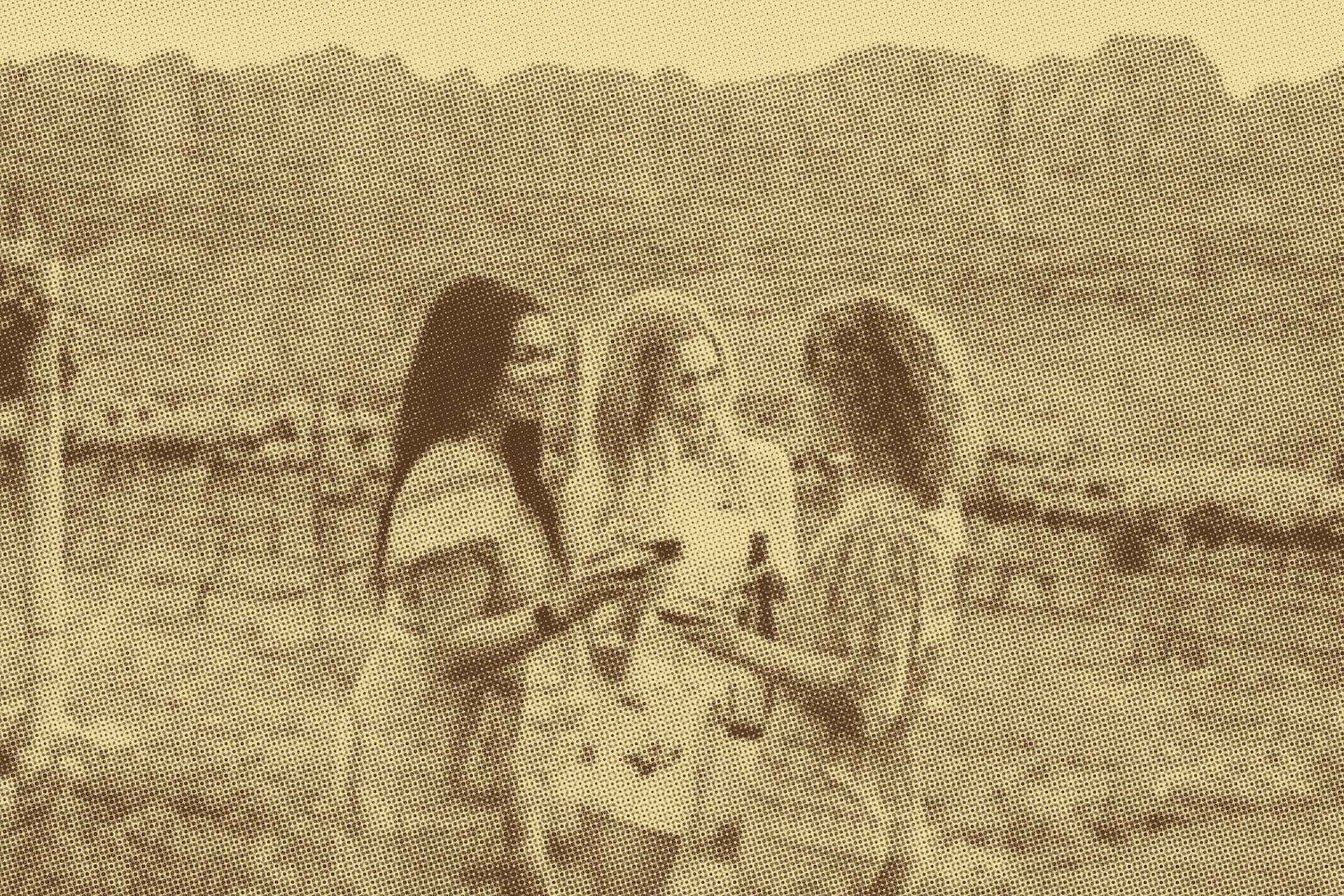 Three women standing side by side holding large seashells in a desert landscape with mountain ranges in the background.