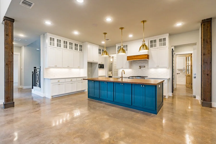 Modern kitchen with a blue island, white cabinets, and gold pendant lights.