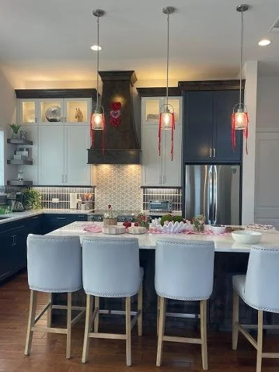 Kitchen island with five white chairs, pendant lights, and Valentine's Day decorations.