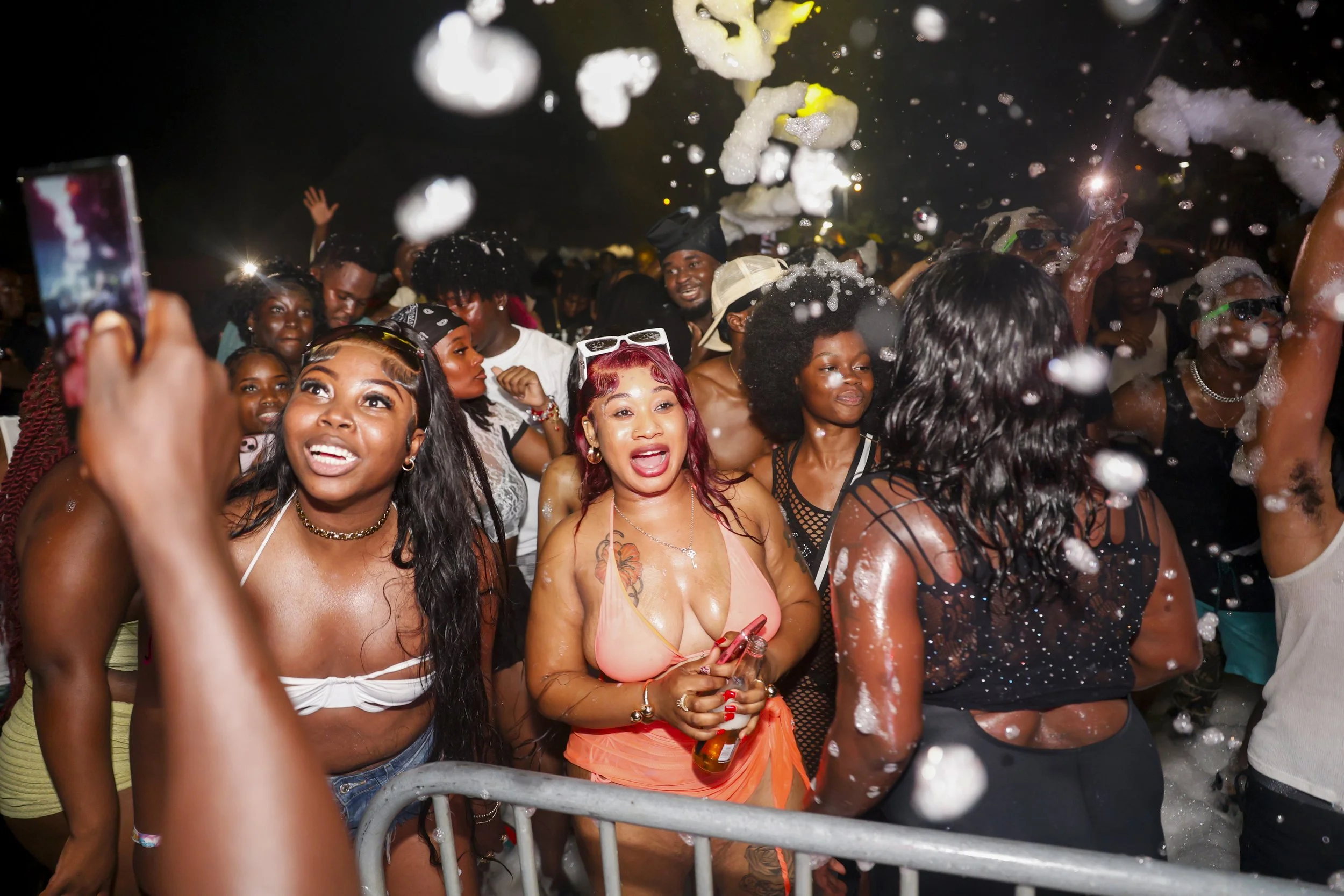 People partying at a nightclub, some with foam on their bodies, dancing and enjoying the music.