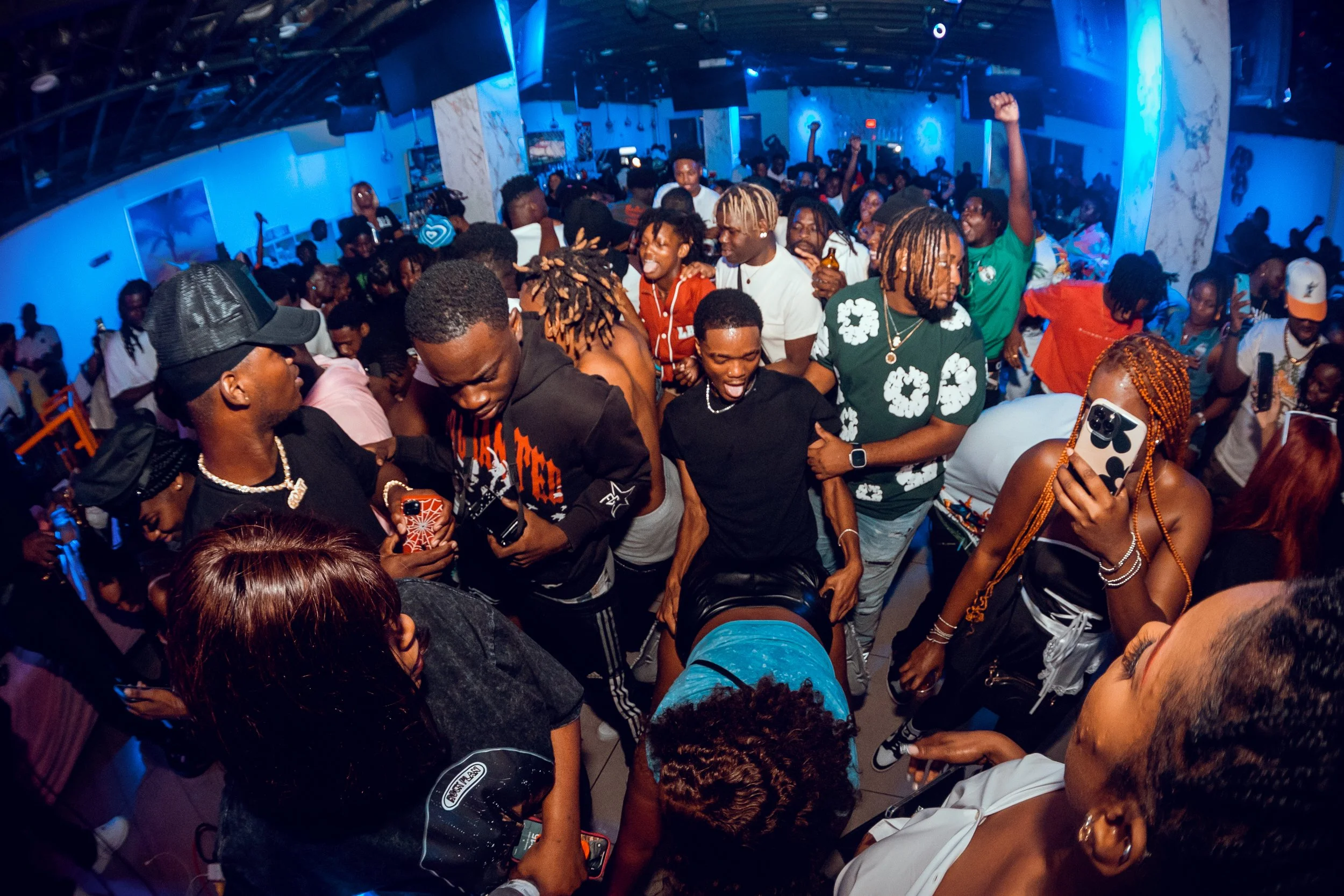 Crowd of people dancing and having fun in a nightclub with blue lighting.