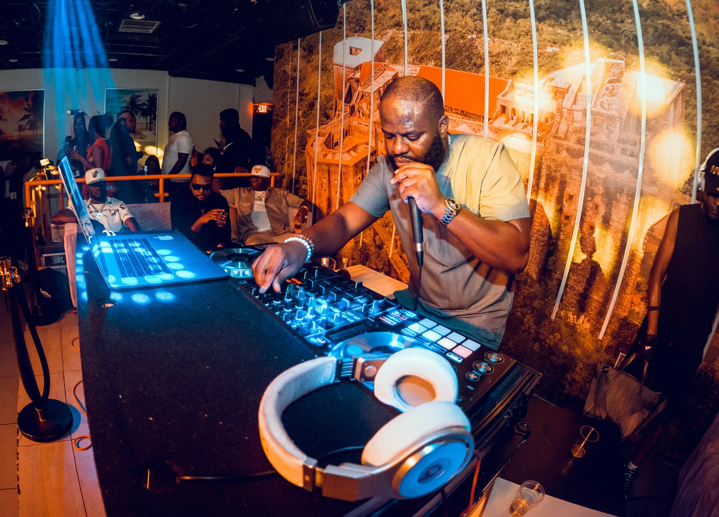 DJ performing at a nightclub, surrounded by people socializing and enjoying the music, with a vibrant, colorful background.