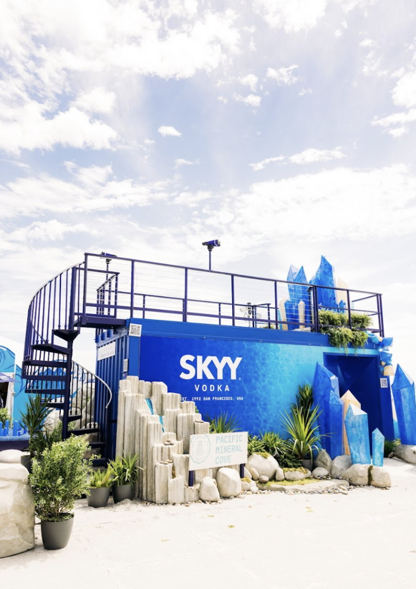 Decorative outdoor display promoting Skyy Vodka, featuring blue crystal-like structures, green plants, rocks, and a sign that reads "Pacific Mineral Cove."