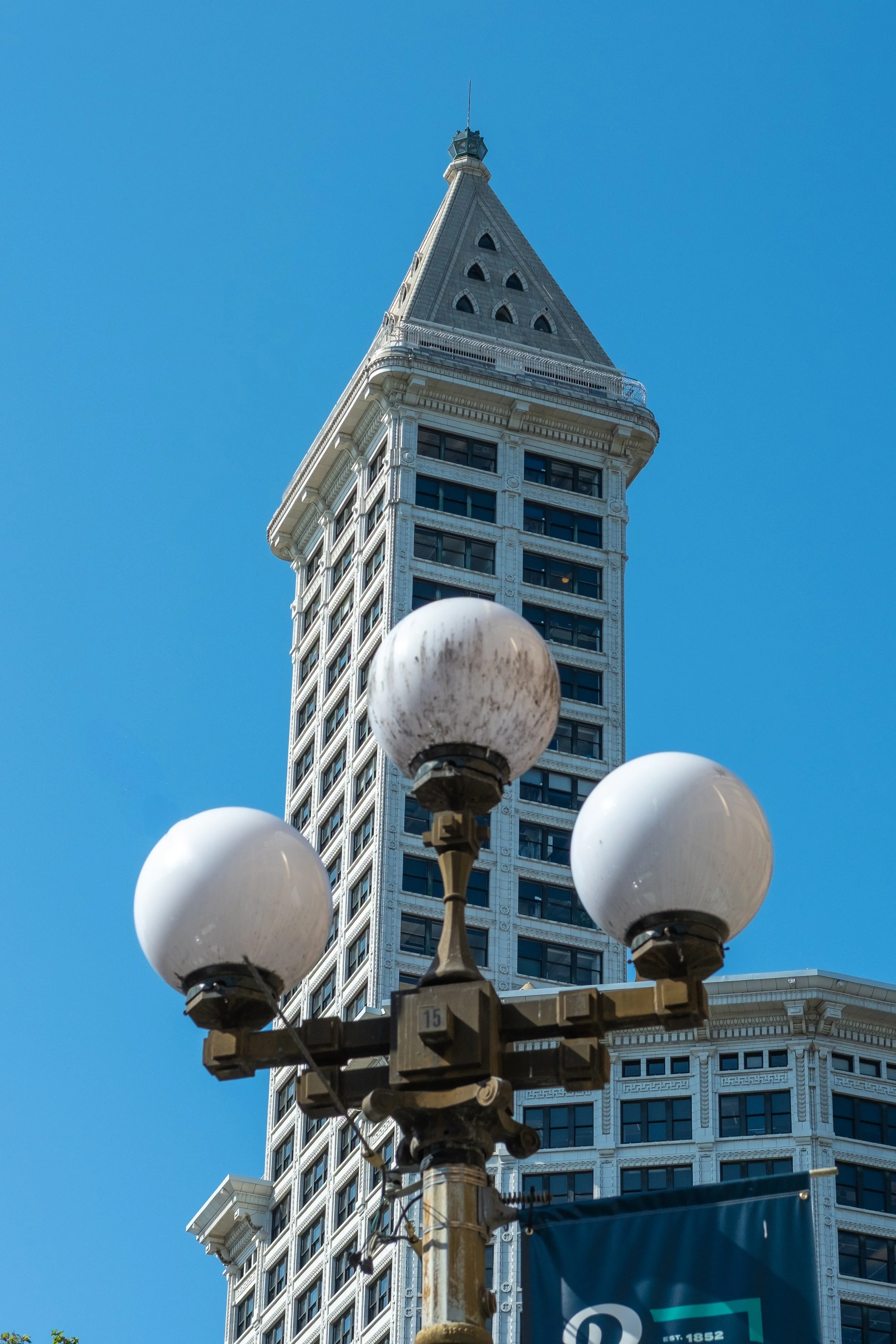 The image shows the historic Flatiron Building in San Francisco with a street lamp in the foreground against a clear blue sky.