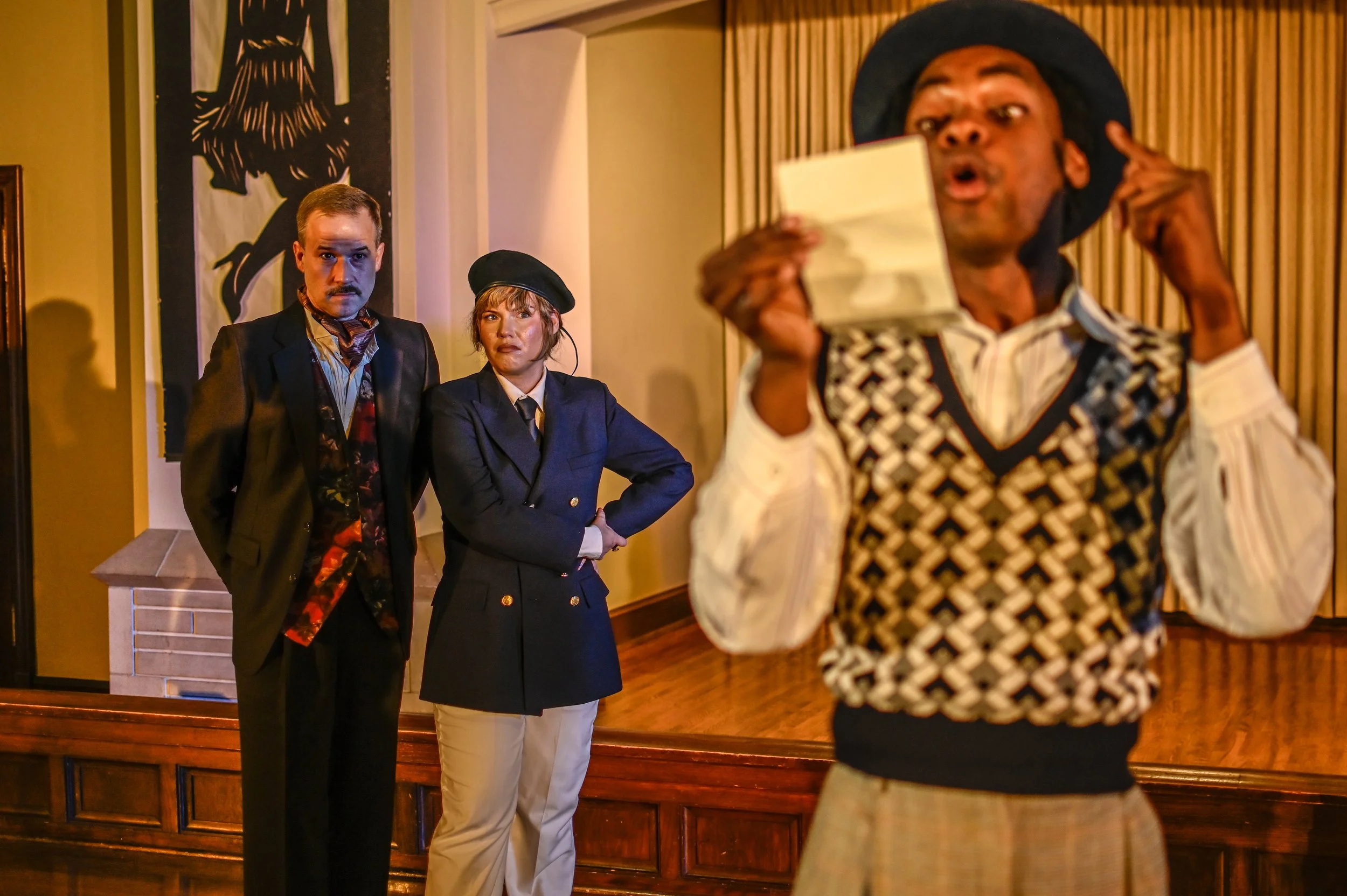Orsino and Viola look on as Feste reads a letter