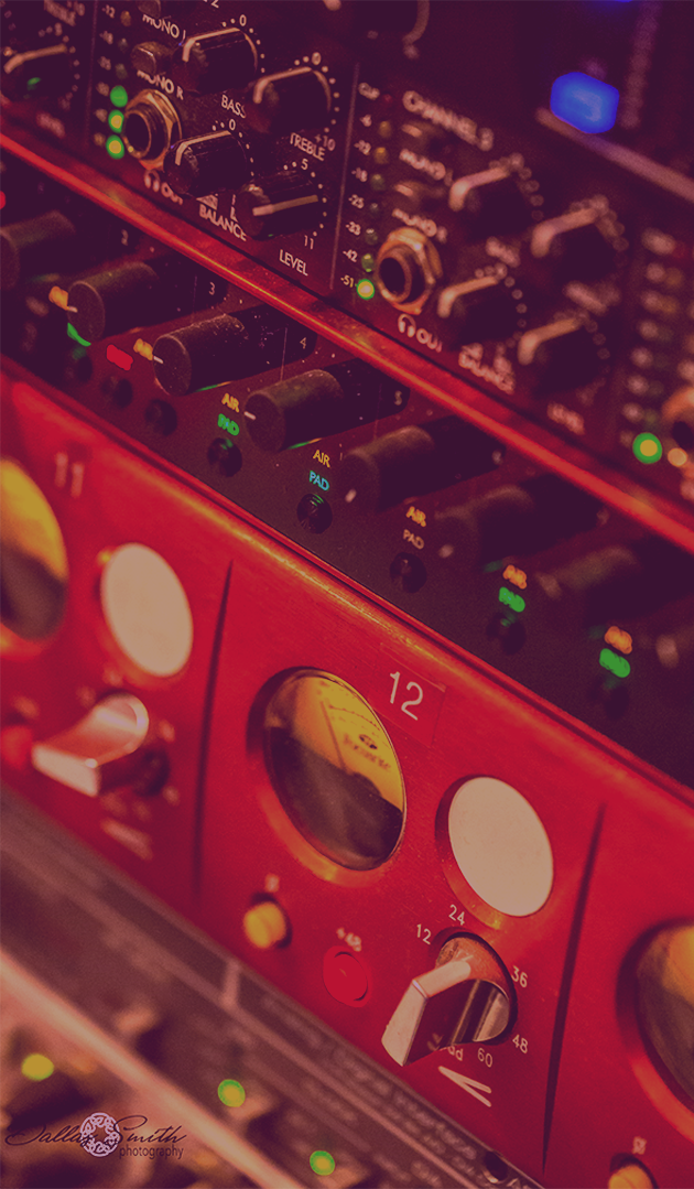 Close-up of a Focusrite 4-channel tube preamp alongside a professional mixing console and audio processors, showcasing precision controls and analog warmth in a high-end recording studio.
