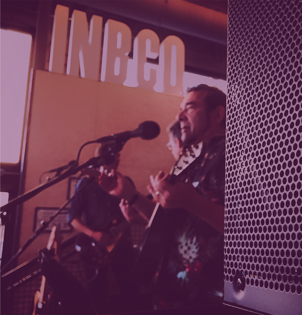 Musicians performing on stage with guitars and microphones, supported by top-of-the-line live sound reinforcement gear delivering powerful, high-fidelity audio in a professional performance setting.