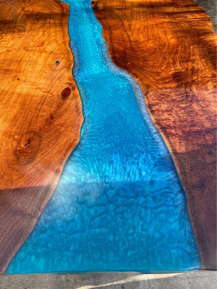 Close-up of a wooden table with a blue resin river in the center.