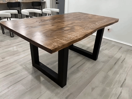 A large wooden table with black metal legs in a room with light-colored flooring and white walls.