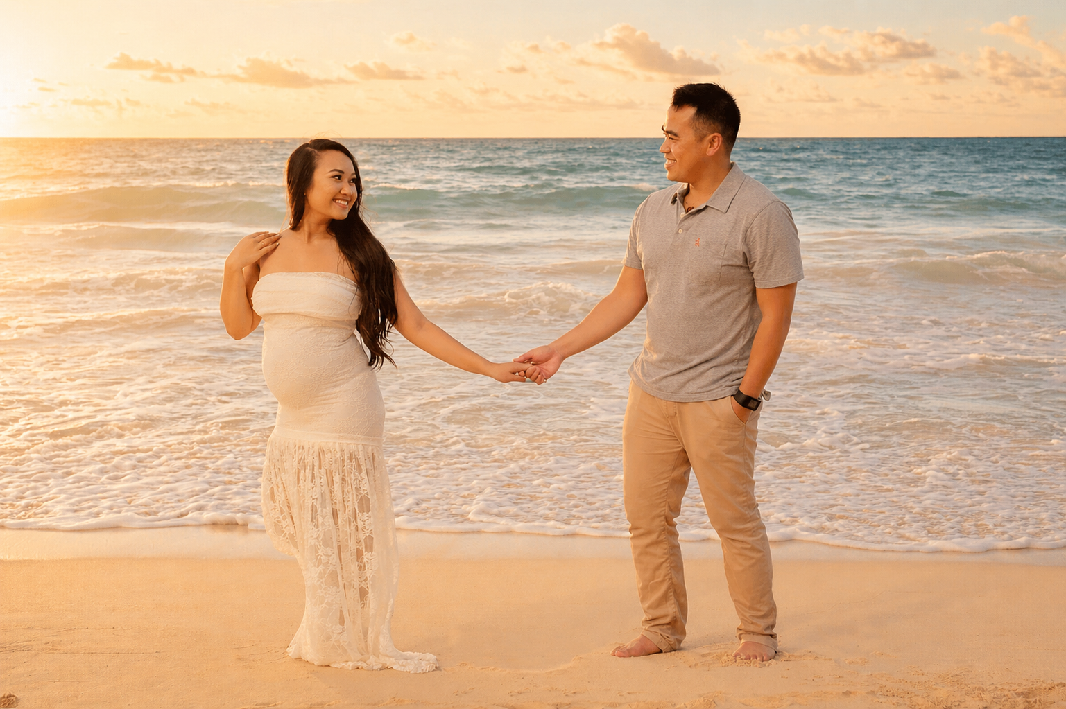 A couple holding hands on the beach during sunset, with waves in the background.