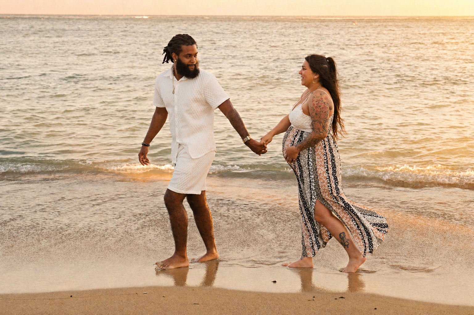 A couple holding hands and walking on the beach during sunset, with the ocean behind them.