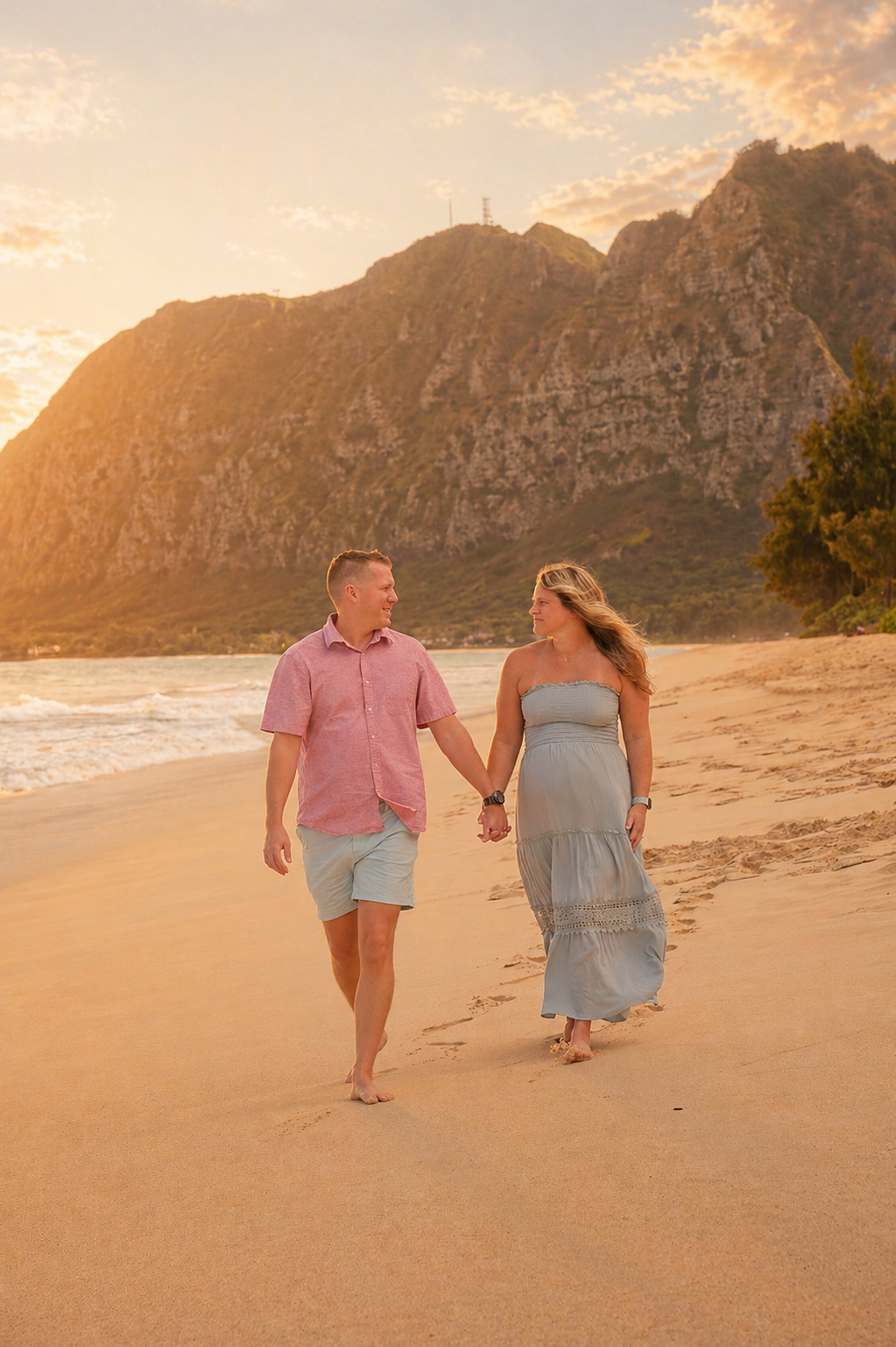 A couple walking hand in hand along a beach at sunset, with mountains in the background.