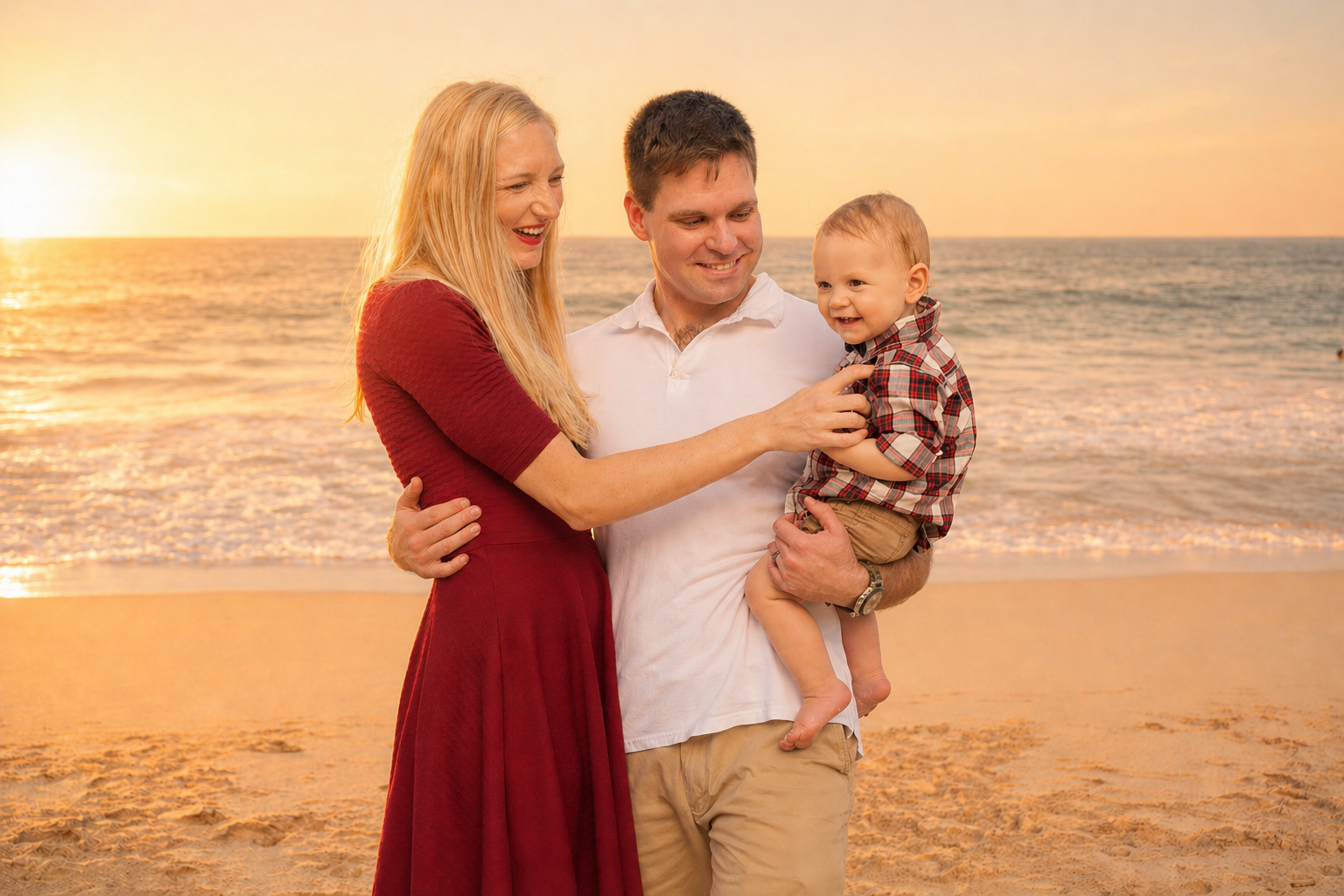 A family of three enjoying a sunset on the beach, with the mother, father, and young son smiling and playing together.