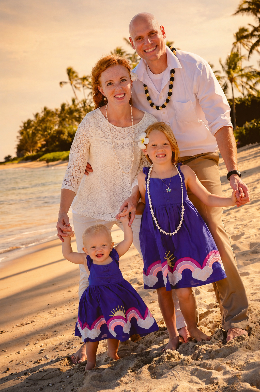 A happy family of five enjoying a beach sunset, holding hands and smiling at the camera. The mother and father stand behind their two young daughters, all dressed in colorful summer attire with tropical accessories. Palm trees and the ocean are visib