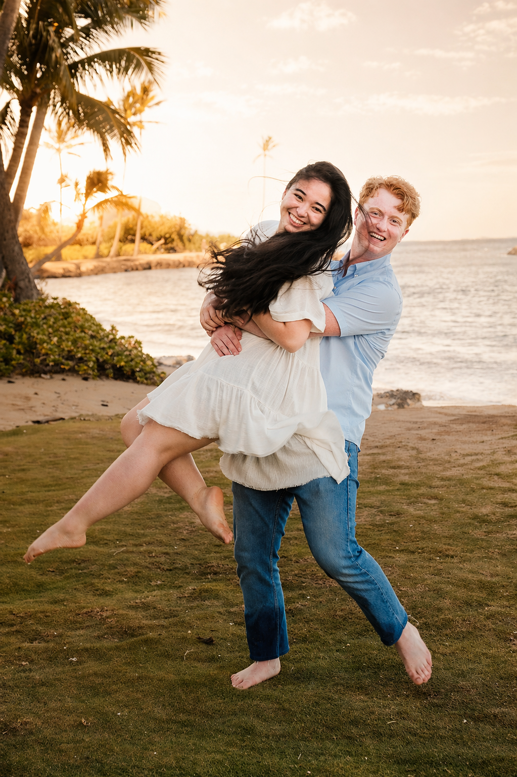 A couple happily embracing on a beach at sunset, with palm trees and ocean in the background.