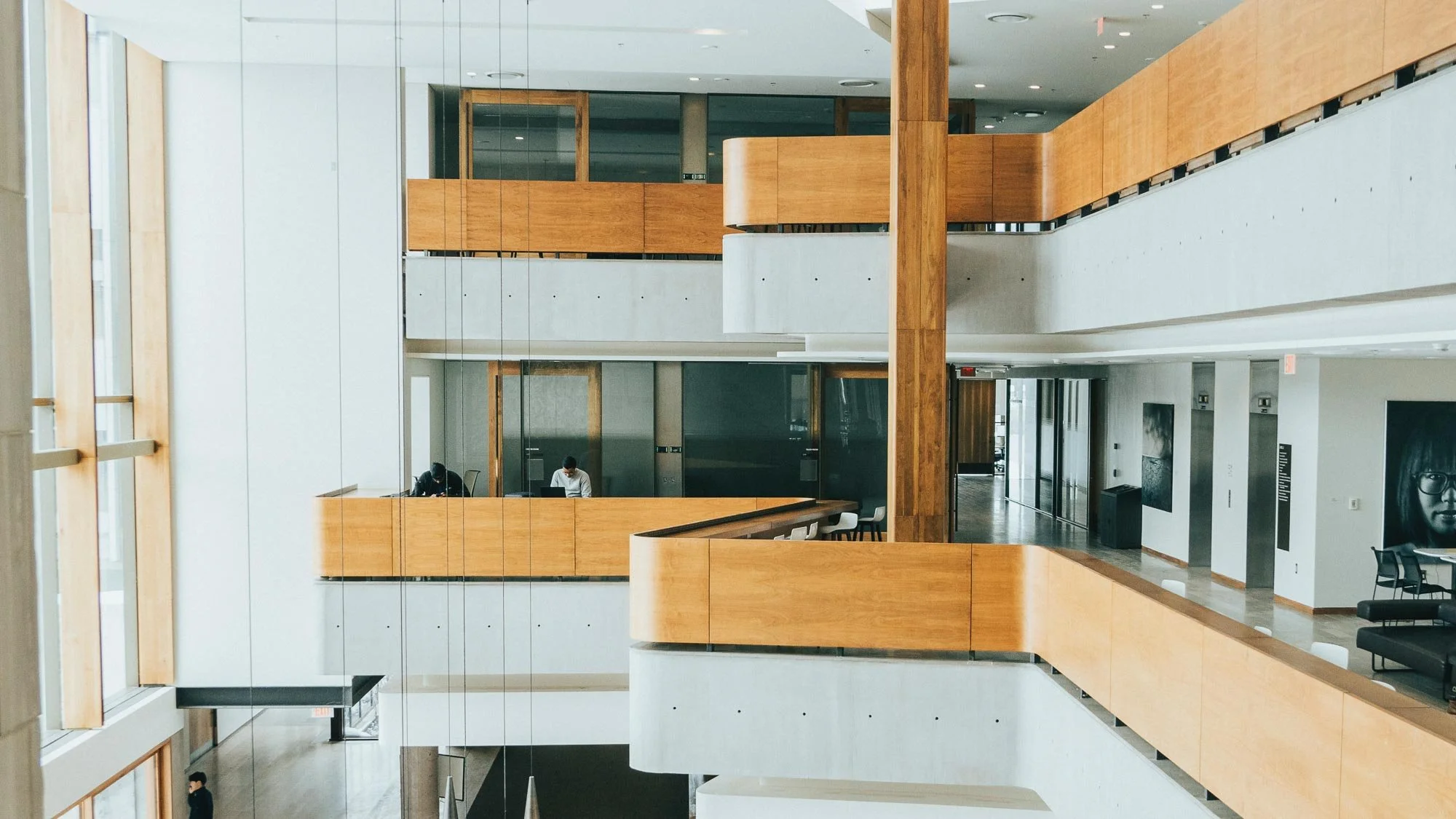 Interior of a modern multi-story building lobby with wooden accents, glass walls.
