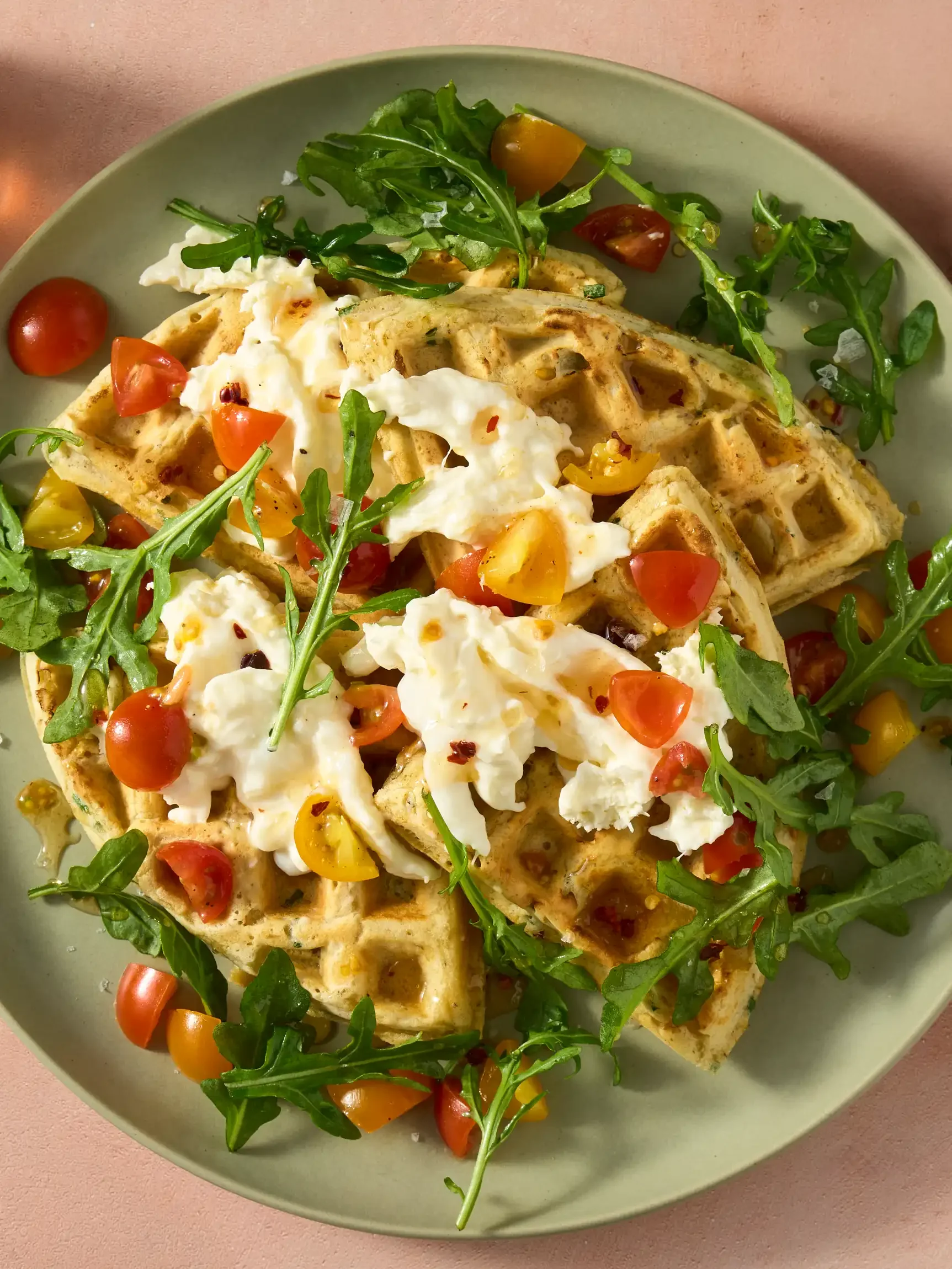 Waffle topped with hot honey,  cherry tomatoes, arugula, fresh mozzarella, and herbs on a green plate. By New York & New Jersey Food Photographer & Stylist Team.