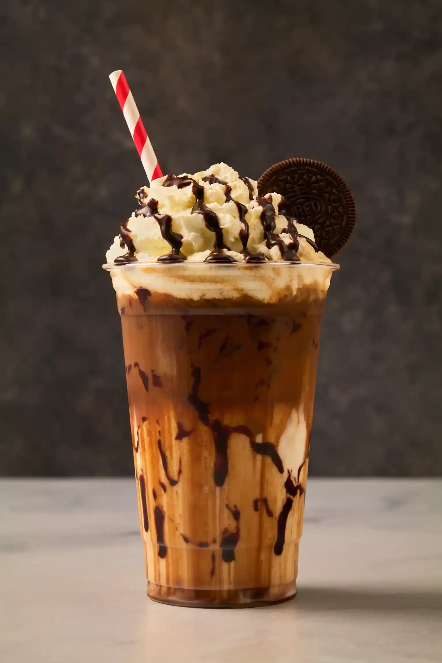 Chocolate iced coffee topped with whipped cream, chocolate drizzle, an Oreo cookie, and a striped straw. By Philadelphia, PA, & NJ coffee drink photographer & coffee drink stylist team Bartholomew Studio.