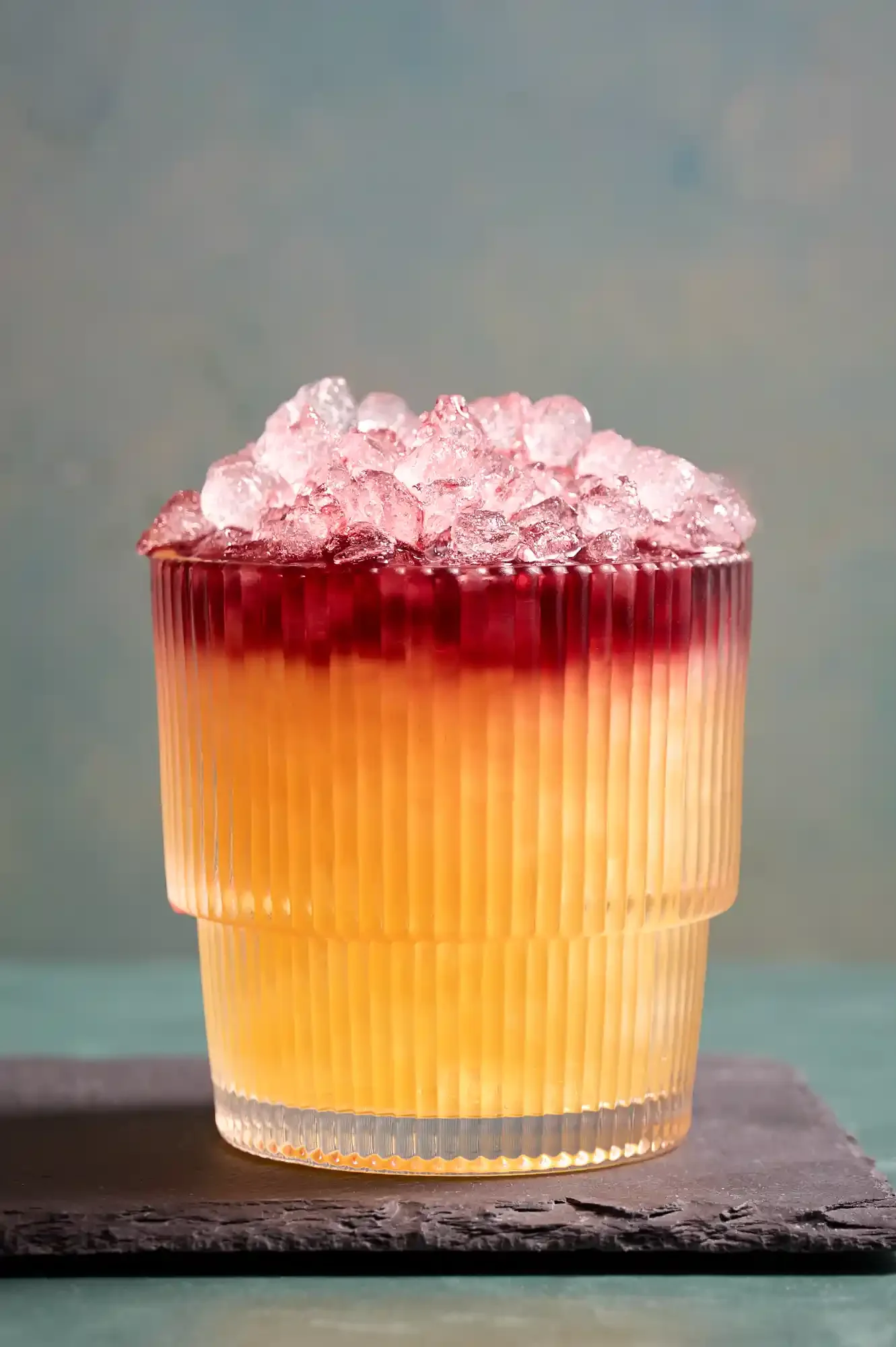 A layered cocktail in a textured glass filled with crushed ice on top. By Philadelphia, PA cocktail photographer & cocktail stylist team Bartholomew Studio.