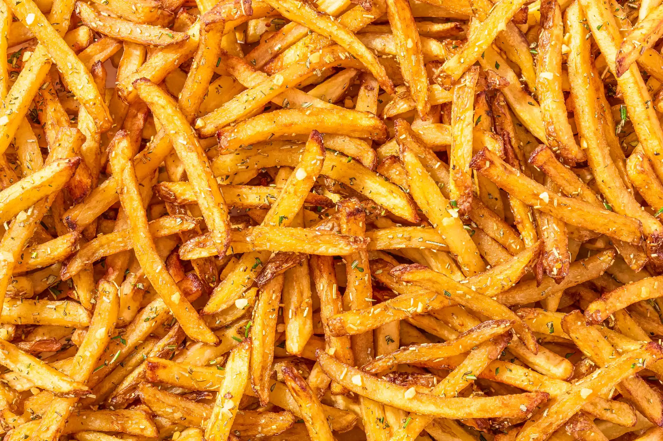 Close-up of freshly cooked, crispy French fries seasoned with herbs and garlic. By Pittsburgh, PA food photographer & food stylist team Bartholomew Studio.