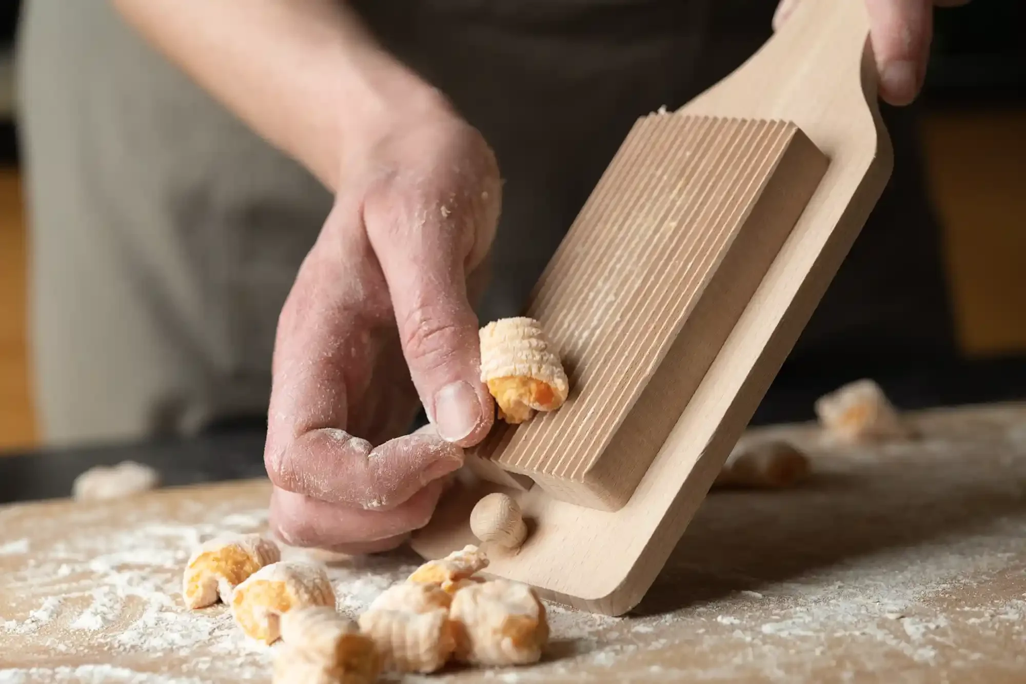 A person using a wooden gnocchi board to shape small pieces of dough into gnocchi. By Philadelphia, PA food photographer & food stylist team Bartholomew Studio.