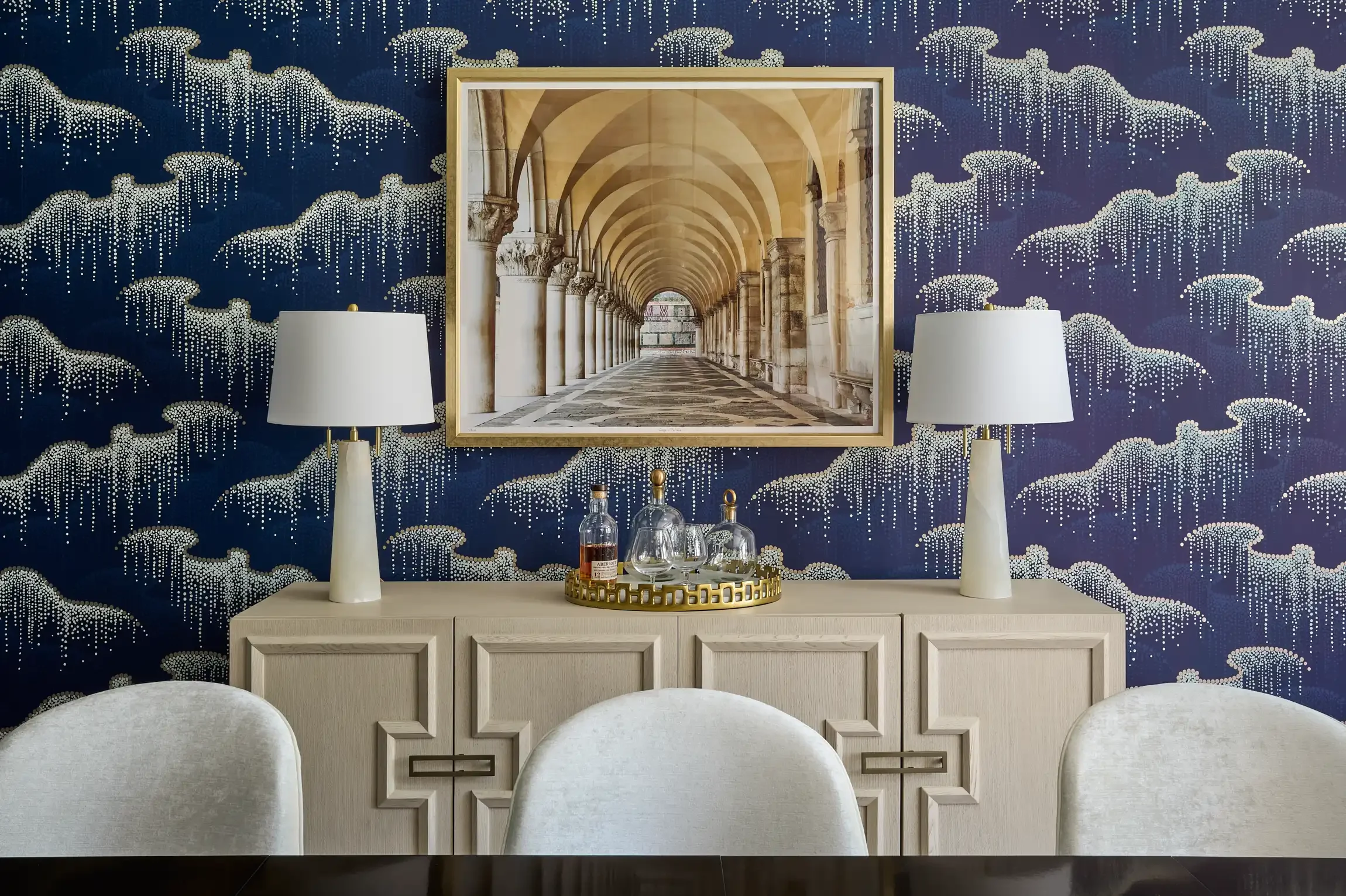 A decorated interior with a navy blue wallpaper featuring white dotted cloud patterns. Design by Wostbrock Home.