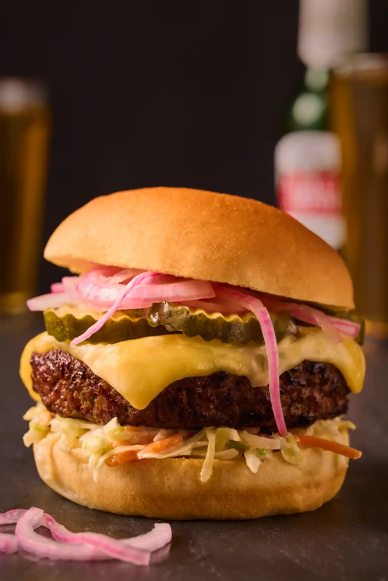 Close-up of a cheeseburger with pickles, onions, cheese, and coleslaw in a bun By Philadelphia, PA & NJ food photographer & food stylist team Bartholomew Studio.