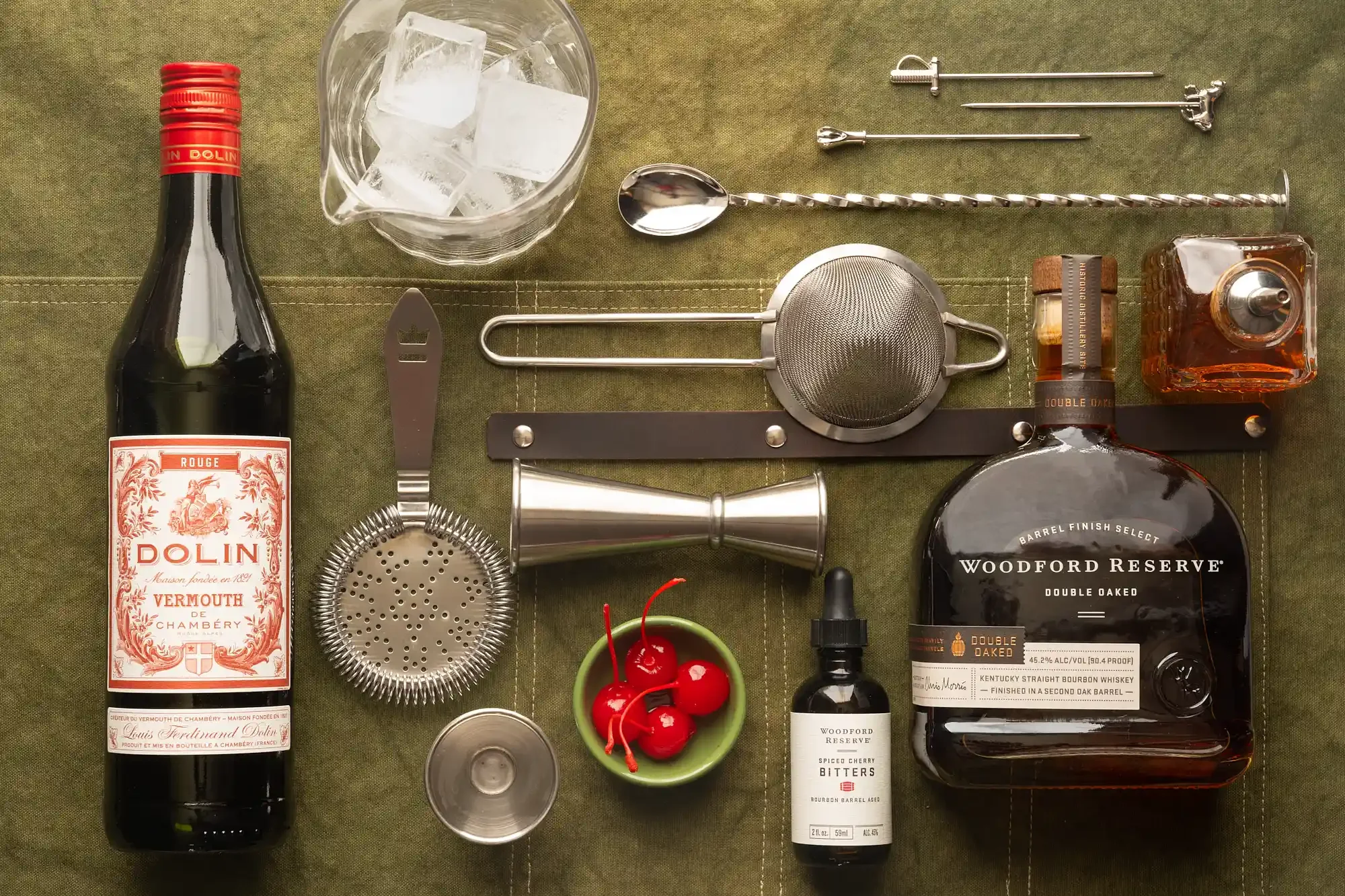A collection of cocktail-making tools and ingredients on a green fabric surface. By Pennsylvania & New Jersey drink photographer & drink stylist team Bartholomew Studio.