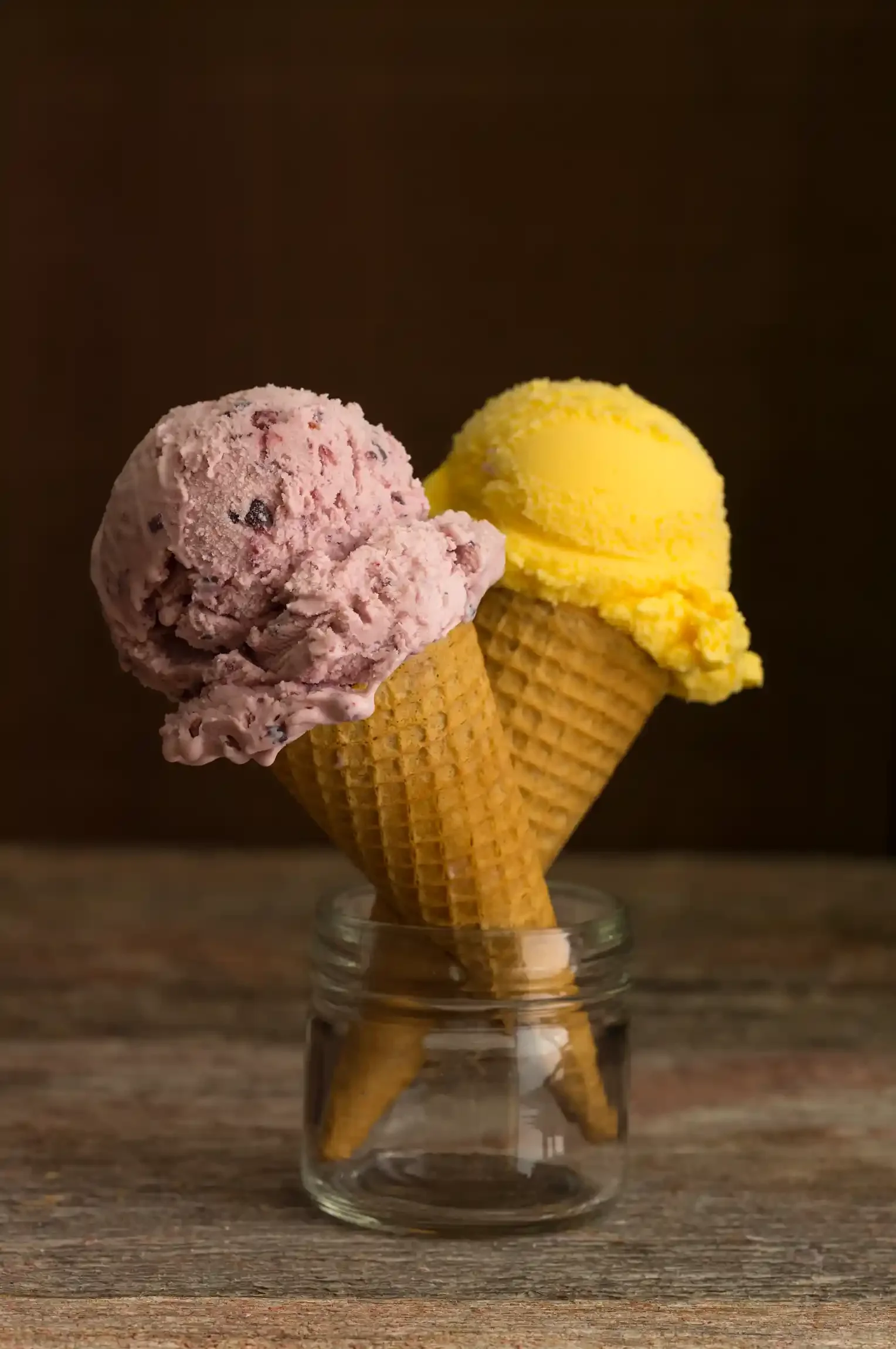 Two scoops of ice cream in waffle cones placed in a glass jar on a wooden surface. By Philadelphia, PA food photographer & food stylist team Bartholomew Studio.