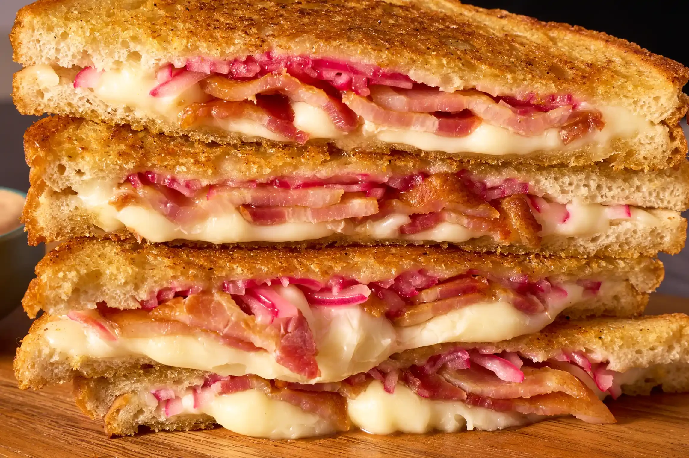 Close-up of a stacked pickled red onion & cheese sandwich, with melted cheese oozing out. By Philadelphia, PA & NJ food photographer & food stylist team Bartholomew Studio.