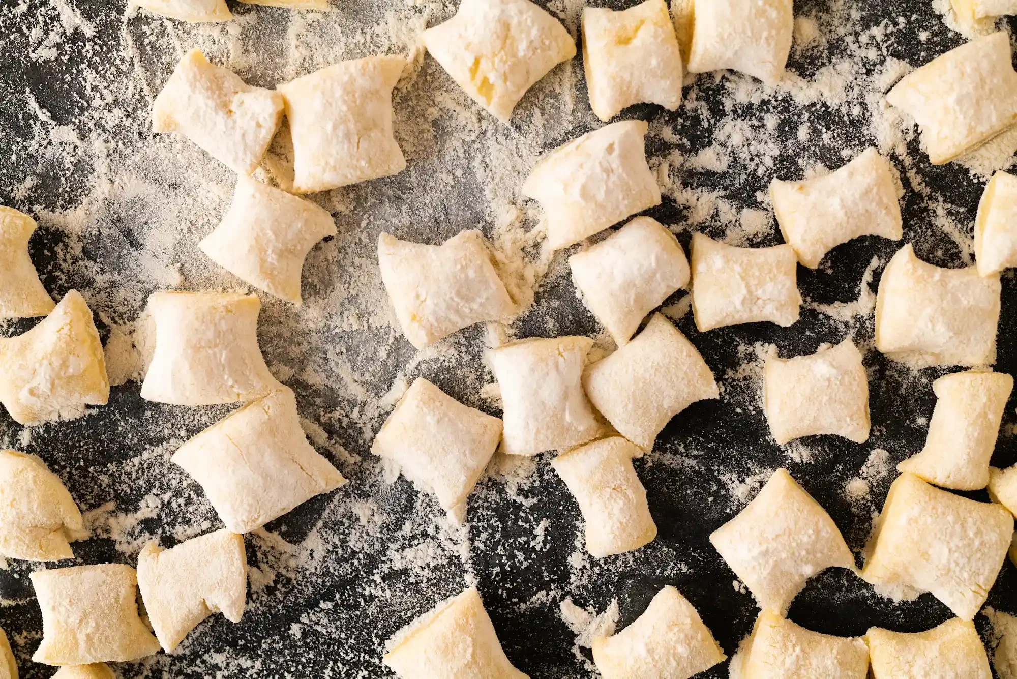 Diced uncooked gnocchi on a floured surface. By Philadelphia, PA food photographer & food stylist team Bartholomew Studio.