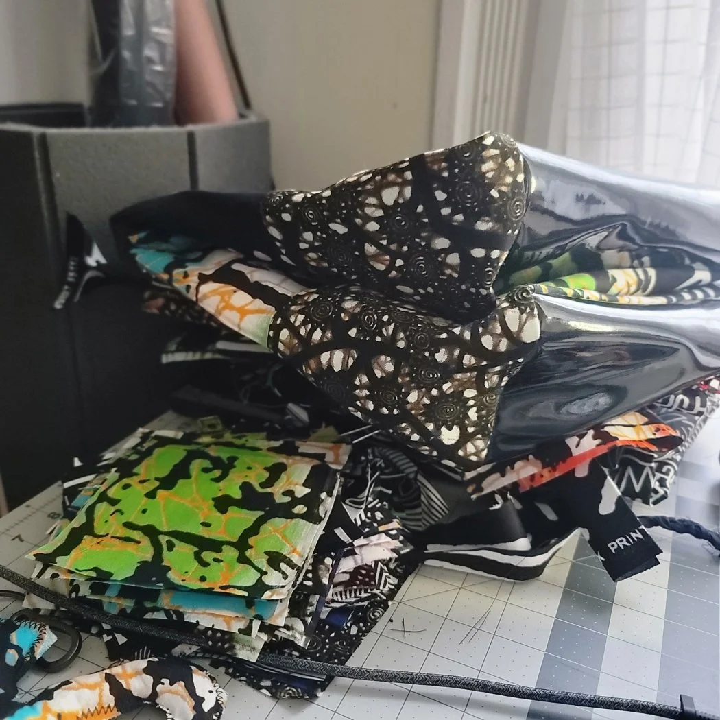 Stack of folded fabric with various colorful and black-and-white patterns on a cutting mat in a craft room.